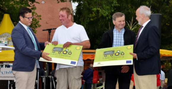 Minister Peter Hauk MdL (links) mit Landrat Thomas Reumann bei der Übergabe von Lernort Bauernhof-Schildern an zwei Betriebsleiter auf dem Kartoffelfest in St. Johann. 