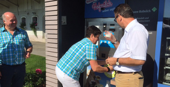 Minister Hauk kostet die Milch an der Milchtankstelle, die die Familie Bohner betreibt.  