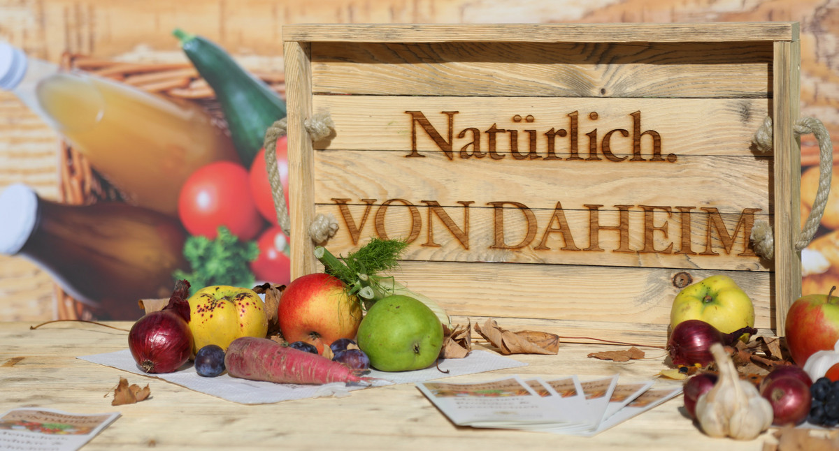 Obst und Gemüse liegen auf einem Tablett mit der Aufschrift „Natürlich. VON DAHEIM“