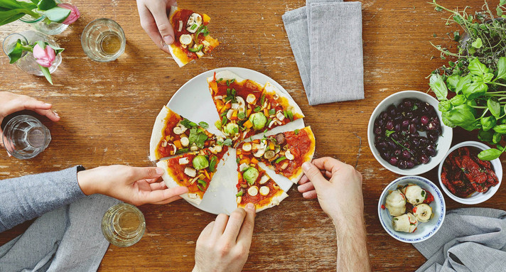 three people sharing organic delicious pizza at dinner party